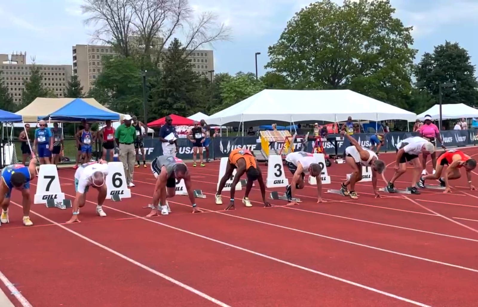Sprinters set in the starting blocks on a red athletics track at the start of a race.
