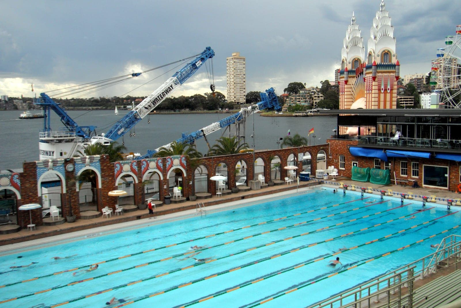 An Olympic swimming pool with marked lanes beside a harbour.
