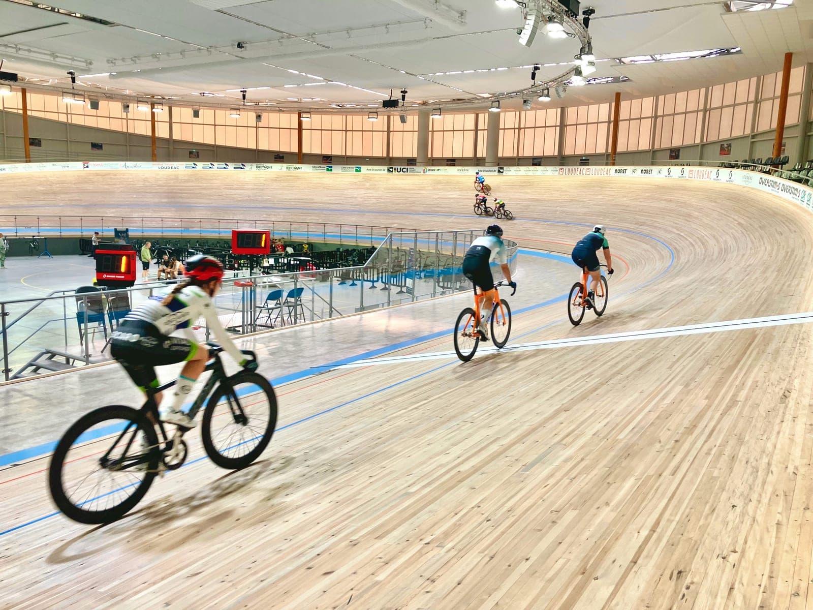 Cyclists ride the banked wooden track inside an indoor velodrome.