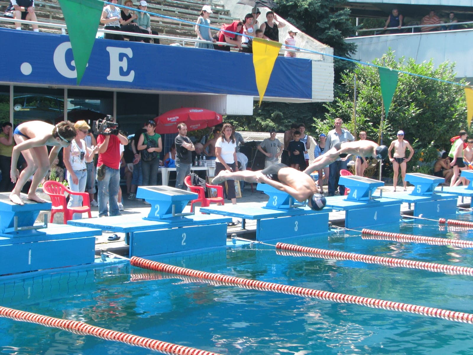 A row of swimmers dive off the starting blocks at the start of a race.