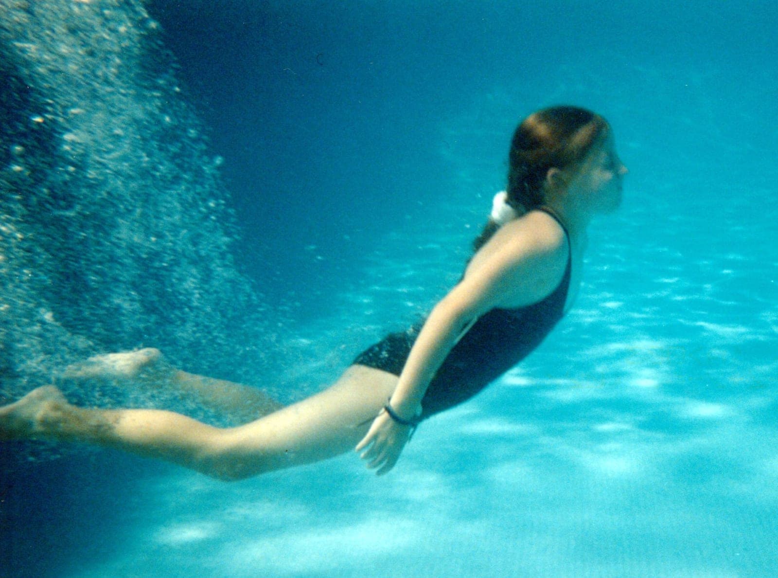 A swimmer glides underwater through a pool.