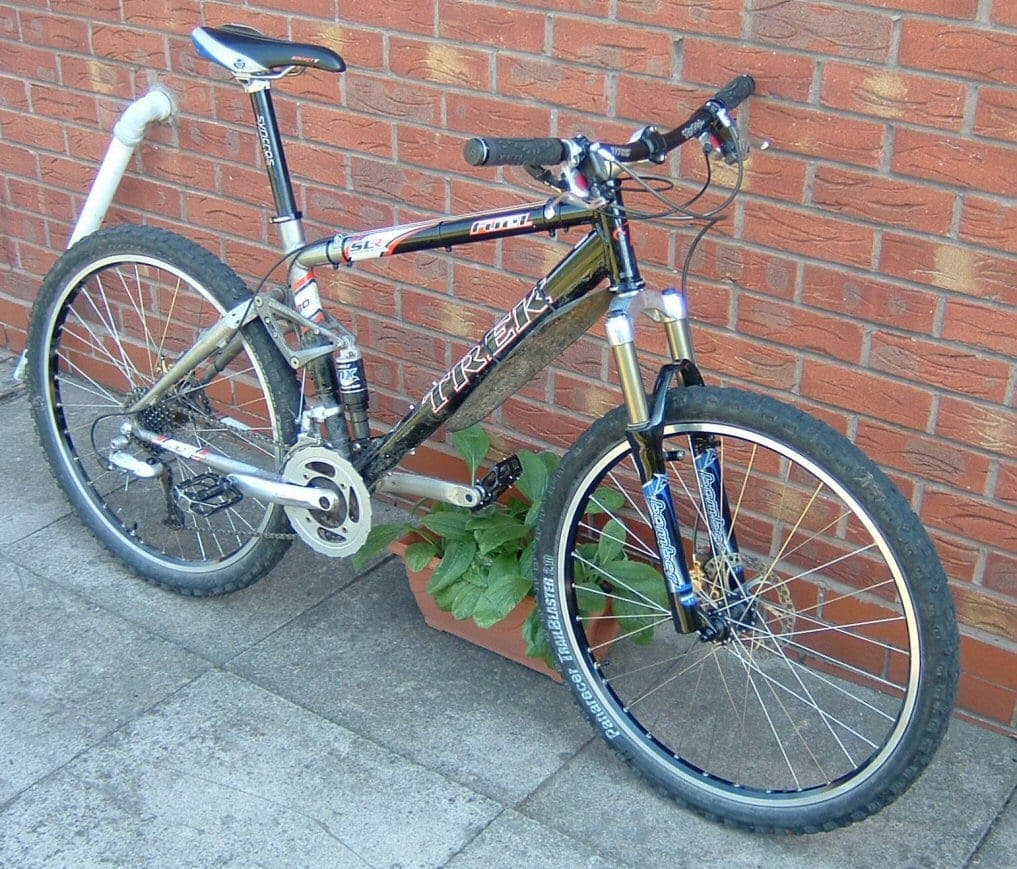 A full-suspension mountain bike leaning against a wall.