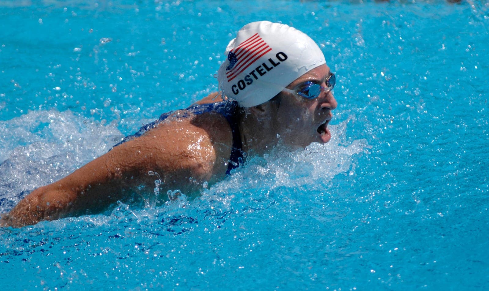 A swimmer competes in a butterfly race, arms sweeping out of the water.
