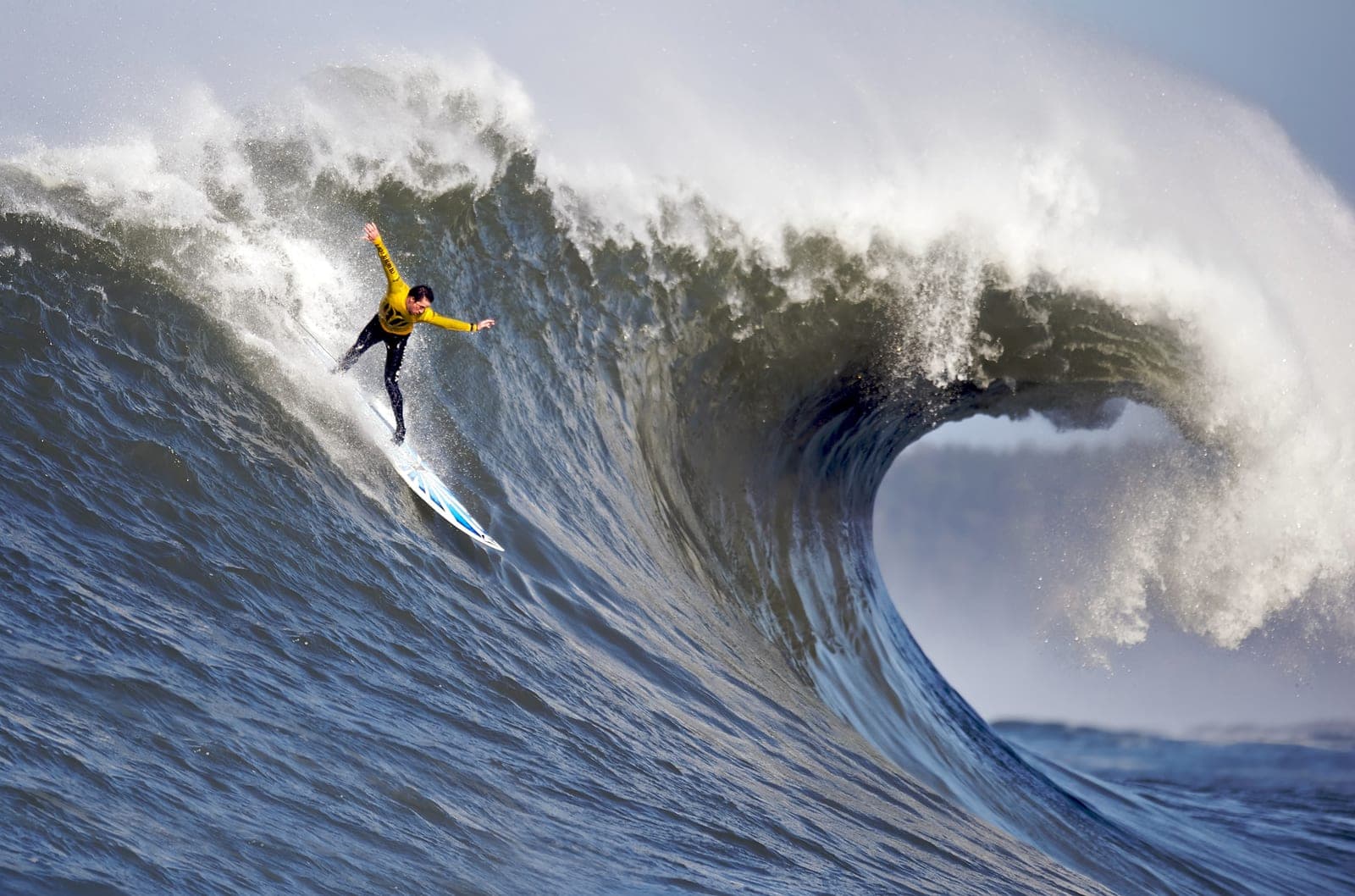 A surfer rides the face of a large breaking wave.