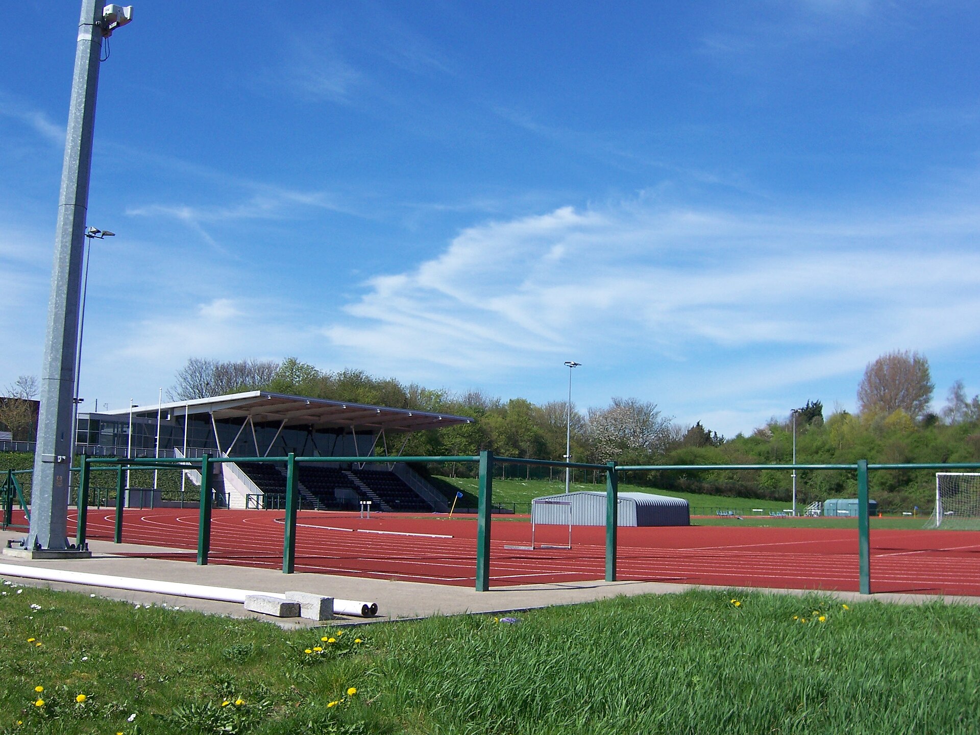 An outdoor synthetic athletics track with white lane markings curving around a green infield.